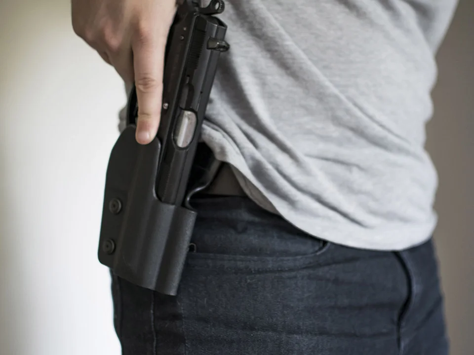 A person wearing a holster with a black handgun